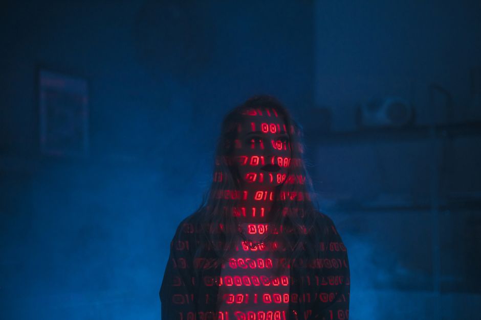 Photograph of a computer screen displaying HTML code in a dark-themed code editor, with visible files and menu options at the top. The code includes tags such as <html>, <head>, <title>, and <link> re